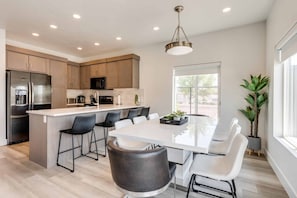 A modern kitchen with a central island, stainless steel appliances, and a large window providing natural light. - Family Reunion Fun #13 and #15 by RedAwning (St. George)