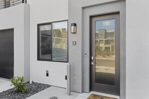 Stylish entrance to a modern residence with a clean design, featuring a dark door and a small window.