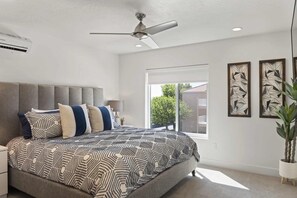 Relax in a stylish bedroom with a large bed, ceiling fan, and beautiful views of the outdoors.