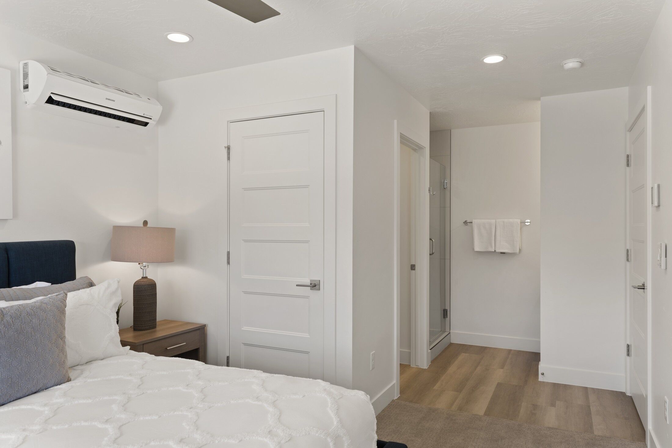 Una camera da letto con un letto, un comodino, una lampada, un condizionatore d'aria e una porta che dà su un bagno.