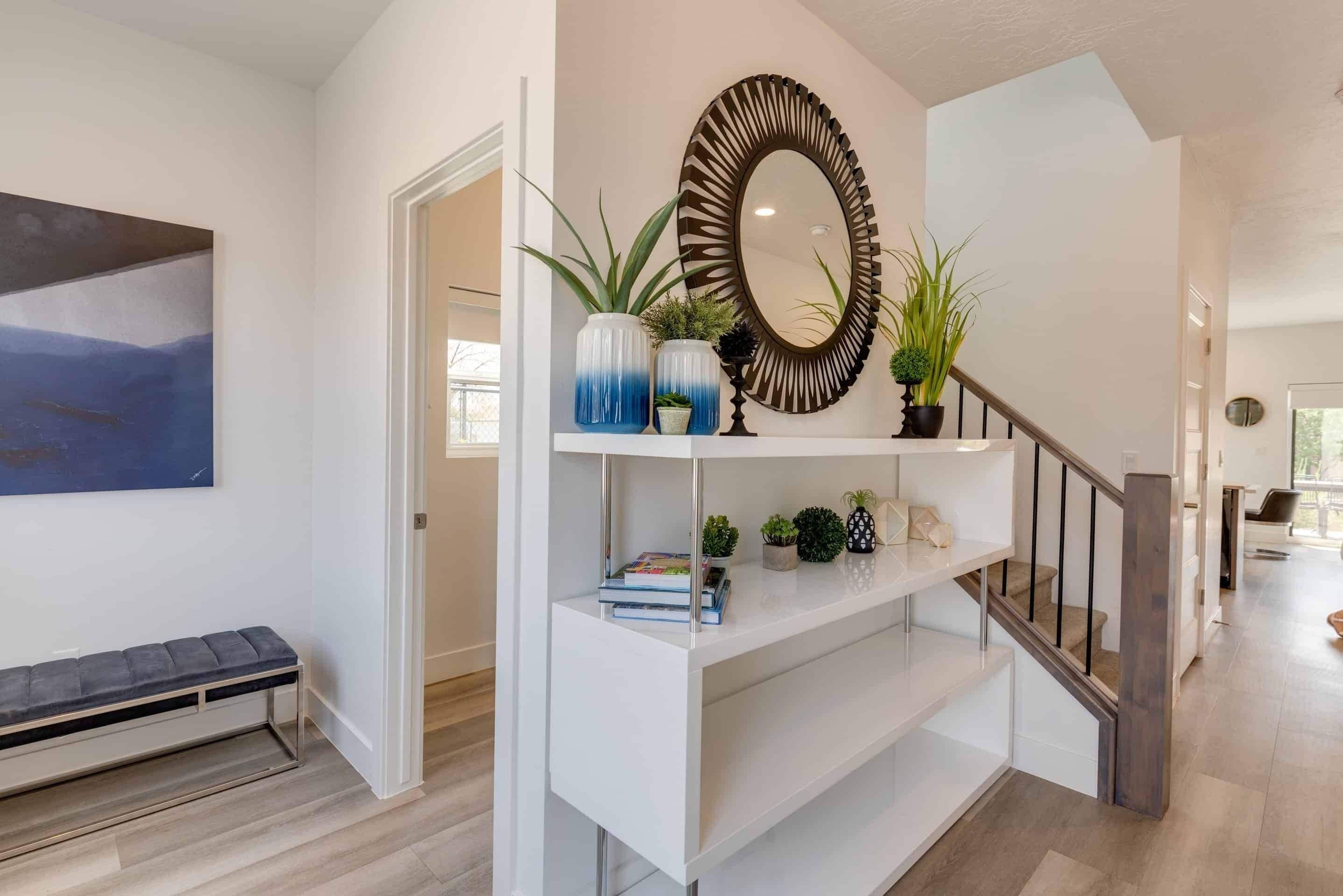 A modern interior with a white console table, a large mirror, and decorative plants.