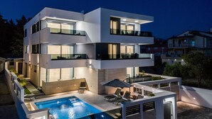 A modern multi-story house with a swimming pool, outdoor seating, and a balcony. - Villa Laverna (Novalja)