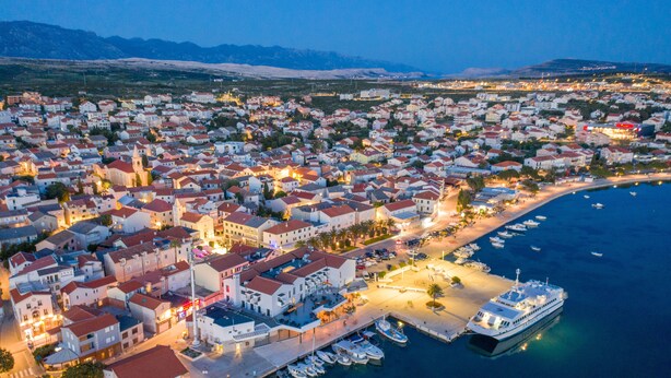 An aerial view of a coastal town with a marina, buildings, and boats. - Villa Laverna (Novalja)