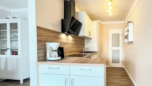 Una cocina moderna con cafetera, armarios blancos y encimera de madera.