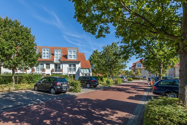 Una calle residencial con casas, coches aparcados y árboles.