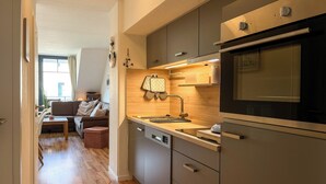 A modern kitchen with a dishwasher, oven, and wooden countertop. - Papillon Wohnung 08-7 (Ostseebad Boltenhagen)