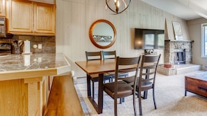 Une cuisine moderne avec des meubles en bois, un plan de travail en marbre et un coin repas comprenant une table et des chaises en bois.