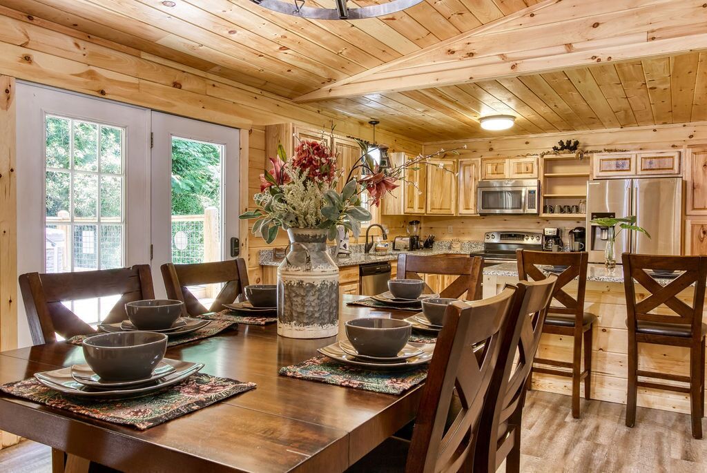 A wooden interior with a dining table set for six, surrounded by wooden chairs.