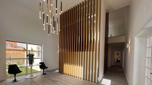 Un interior moderno con un separador de madera, un comedor con mesa y sillas, y vistas al exterior.