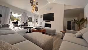 Una sala de estar moderna con un sofá grande, una mesa de centro y un televisor montado en la pared.