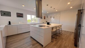 Una cocina moderna con una isla central, armarios blancos y una campana extractora de acero inoxidable.