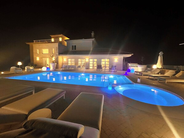 Una piscina amb gandules i un edifici al fons que té diverses finestres i portes.