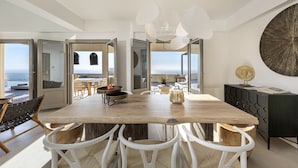 Un comedor amplio con una mesa de madera y sillas blancas, una consola negra y un gran adorno de pared.