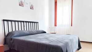 Una camera da letto con un letto, un comodino, una sedia e una finestra con tende.