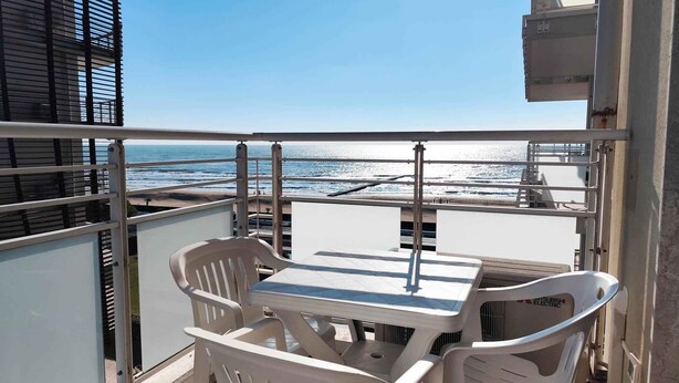 Un balcone con tavolo e sedie vista sull'oceano.