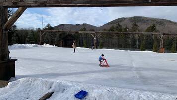 A snowy outdoor area with a wooden structure, a small building, and a person on skis.