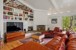 A modern living room with a fireplace, bookshelves, a television, and leather furniture.