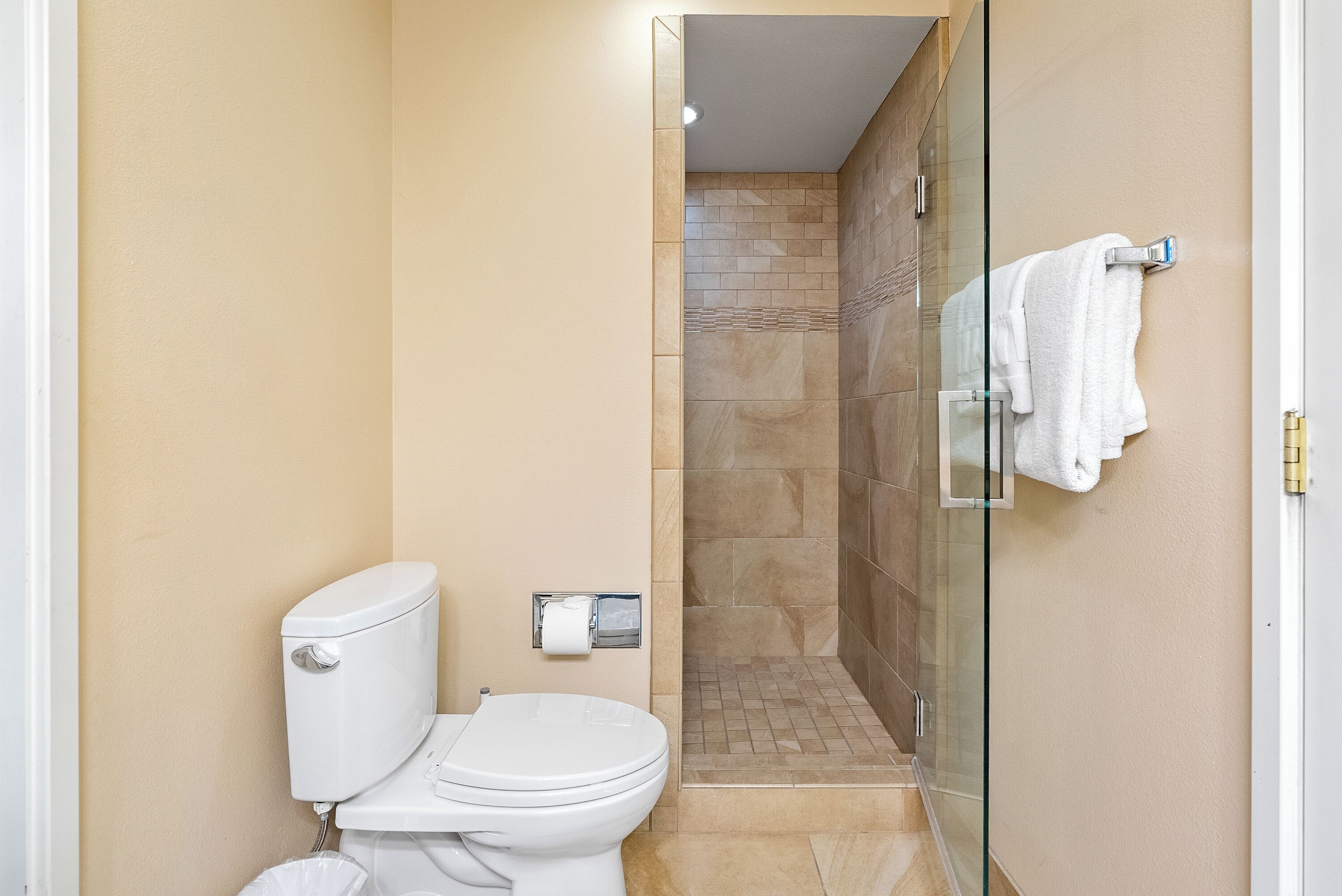 Un baño con inodoro, cabina de ducha de vidrio y perchero para toallas.