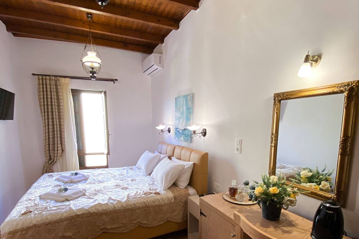 A bedroom with a bed, bedside table, dresser, and a large mirror.