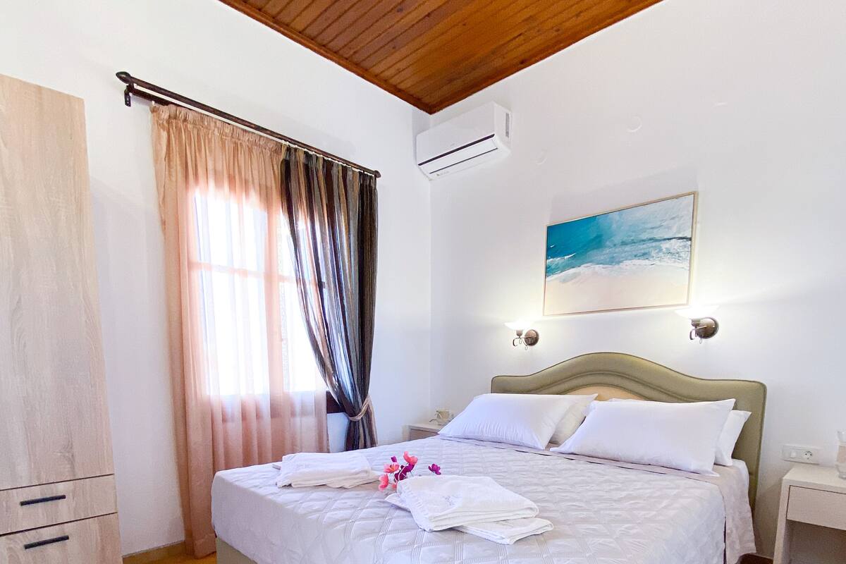 A bedroom with a bed, a nightstand, a wardrobe, and a painting on the wall.