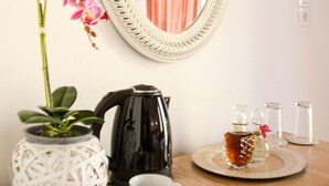 A room with a white woven vase, pink orchids, a black coffee maker, and a tray with a teapot and cups. - Casa Dasyra (Chania)