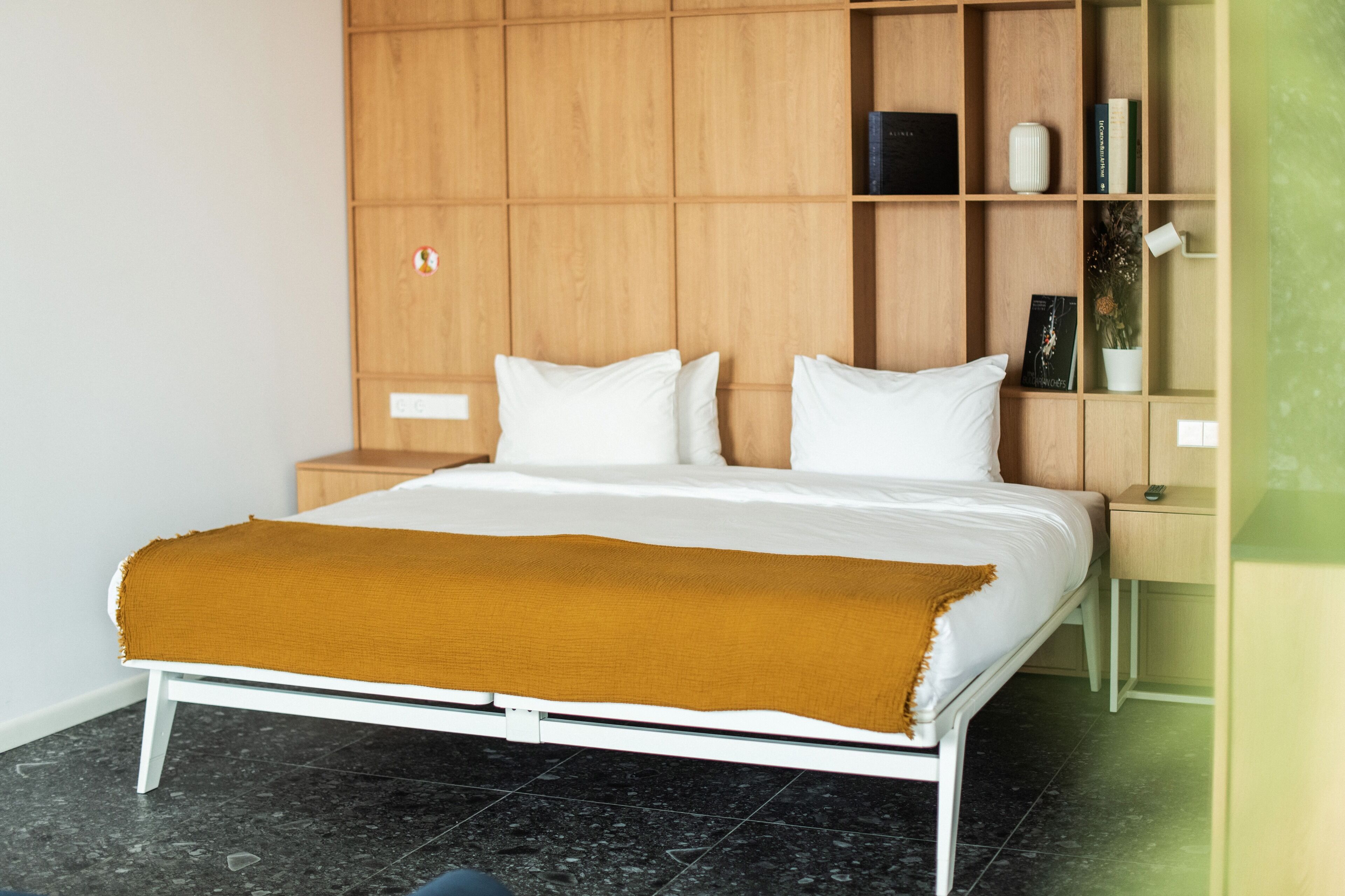 Un dormitorio moderno con una cama, estanterías de madera, una mesita de noche y una pequeña mesa.