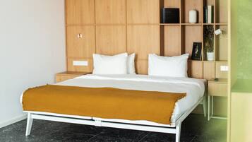 Un dormitorio moderno con una cama, estanterías de madera, una mesita de noche y una pequeña mesa.