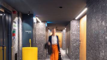 A hotel corridor with a marble wall, a yellow pillar, and a sign pointing to the pool.