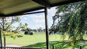 Un espace extérieur abrité offrant une vue sur une pelouse bien entretenue et des arbres.
