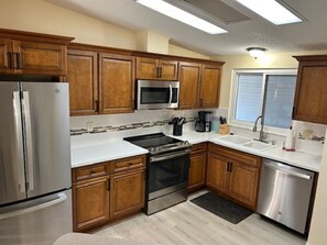 Enjoy cooking in this well-equipped kitchen with a large island, refrigerator, microwave, oven, dishwasher, and sink.