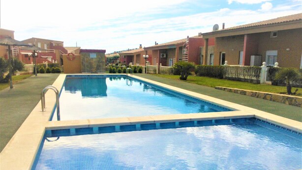 Une piscine rectangulaire avec un escalier en métal sur un de ses côtés, entourée d’un bord en béton peu élevé.
