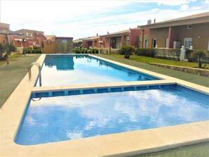 Relax by the pool surrounded by lush greenery and beautifully manicured hedges.