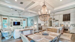 A spacious living room with a large dining table, a chandelier, and a kitchen area with modern appliances. - Pet Friendly Designer Gem with LSV and Bikes 100 Yards to Camp WaterColor (Santa Rosa Beach)