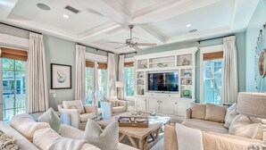 A spacious living room with a large TV, comfortable seating, and a ceiling fan. - Pet Friendly Designer Gem with LSV and Bikes 100 Yards to Camp WaterColor (Santa Rosa Beach)