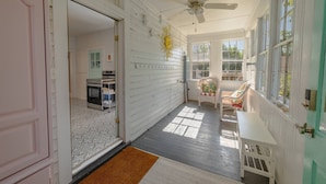 A sunlit porch with a ceiling fan, a white bench, and a chair with a colorful cushion. - Fun in the Sun Home with Game Shed, Near Beach (Cape Charles)