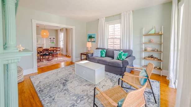 A spacious living room with a grey sofa, wicker chairs, a white coffee table, and a bookshelf. - Fun in the Sun Home with Game Shed, Near Beach (Cape Charles)