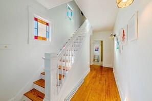 A staircase with white railings and wooden steps leading to a room with a window and a door. - Fun in the Sun Home with Game Shed, Near Beach (Cape Charles)