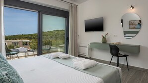 A hotel room with a bed, a desk, a chair, a TV, and a large window offering a view of the outdoors. - Perfect location, private pool, hot tub and gym! (Chania)