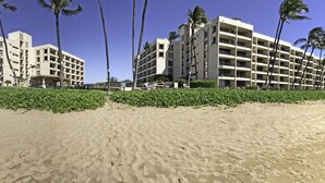 Ein Hotel direkt am Strand mit mehreren Etagen, Palmen und einem Sandstrand.