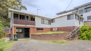 A two-story residential building with a balcony, a front door, and a small front yard with steps leading to the entrance. - Beachside, Pet friendly, Paradise. (Black Head)