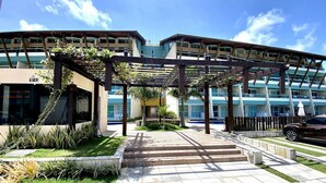 A modern building with a covered walkway and a pool area. - Villas do Atlântico próximo ao mar (Ipojuca)