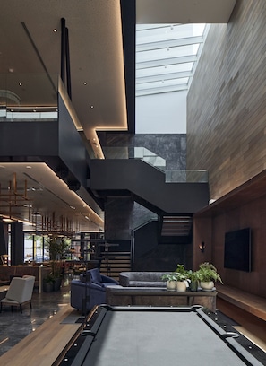 A spacious lobby with a central seating area, a staircase, and a large window allowing natural light.