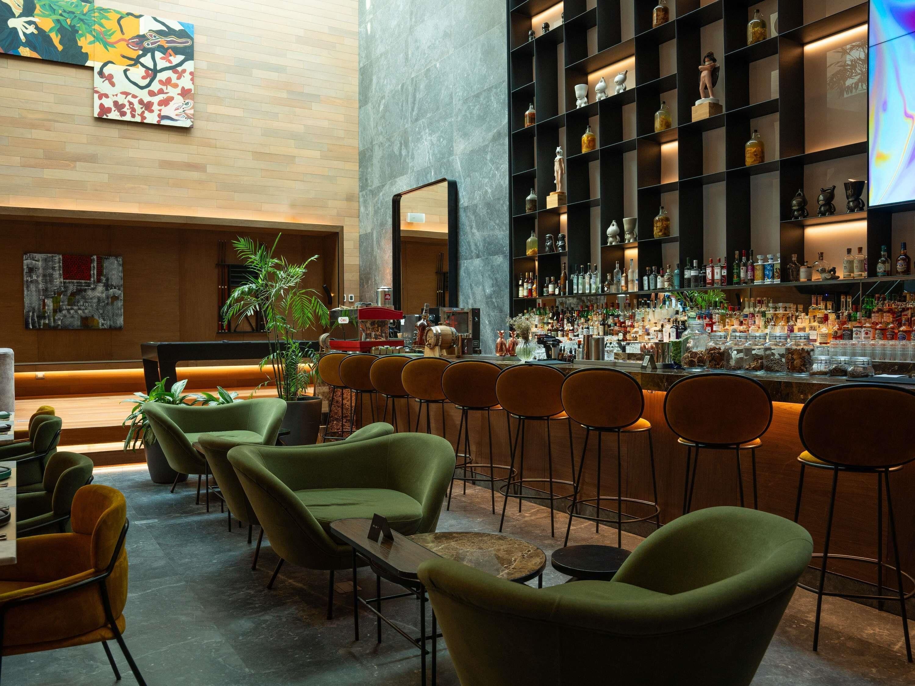 A bar area with seating, a large mirror, and shelves with bottles.