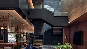 A modern interior with a staircase, seating area, and a large window. - Pullman Lima Miraflores (Lima)