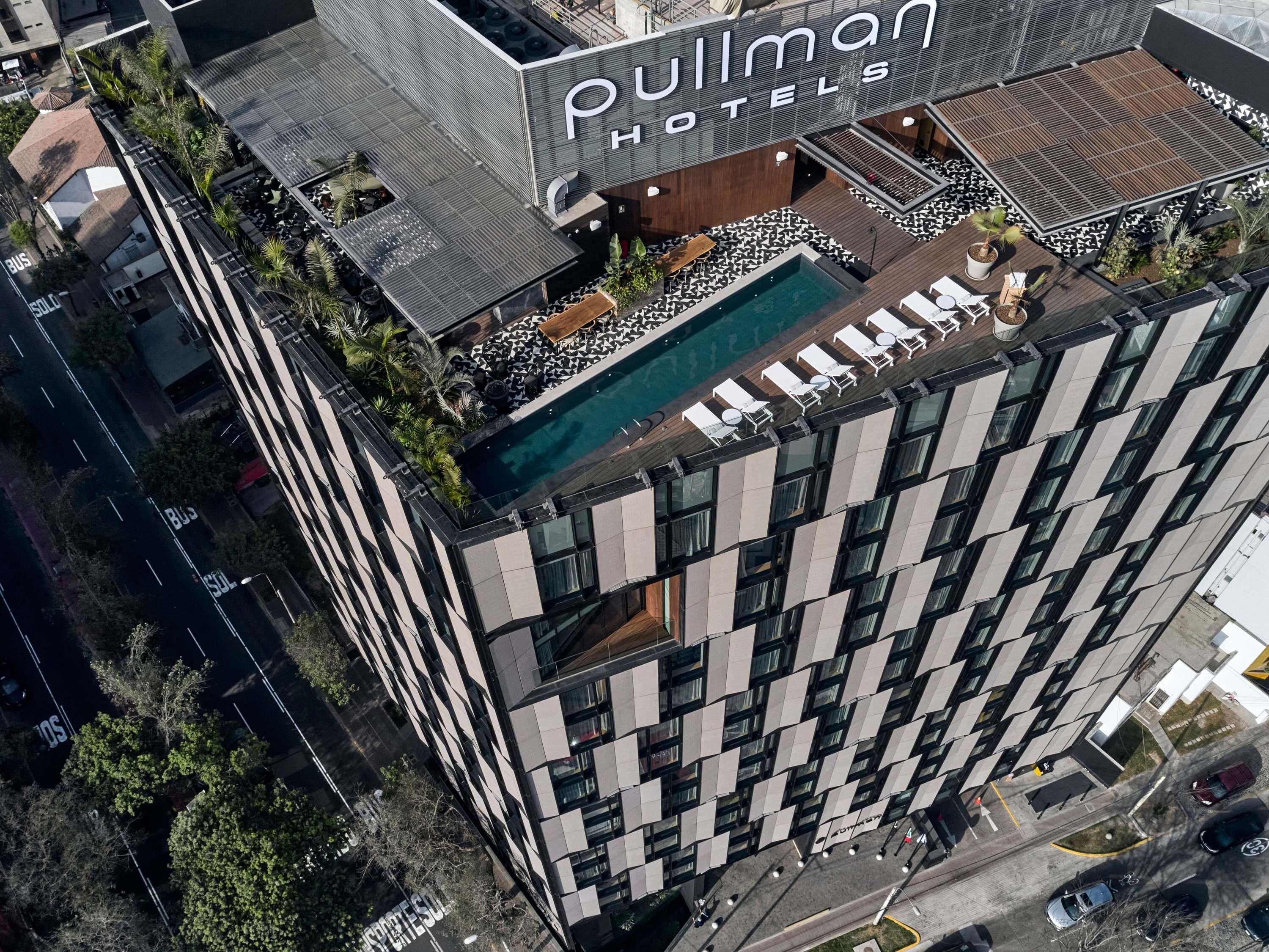 A hotel with a rooftop pool, outdoor seating, and a modern architectural design.