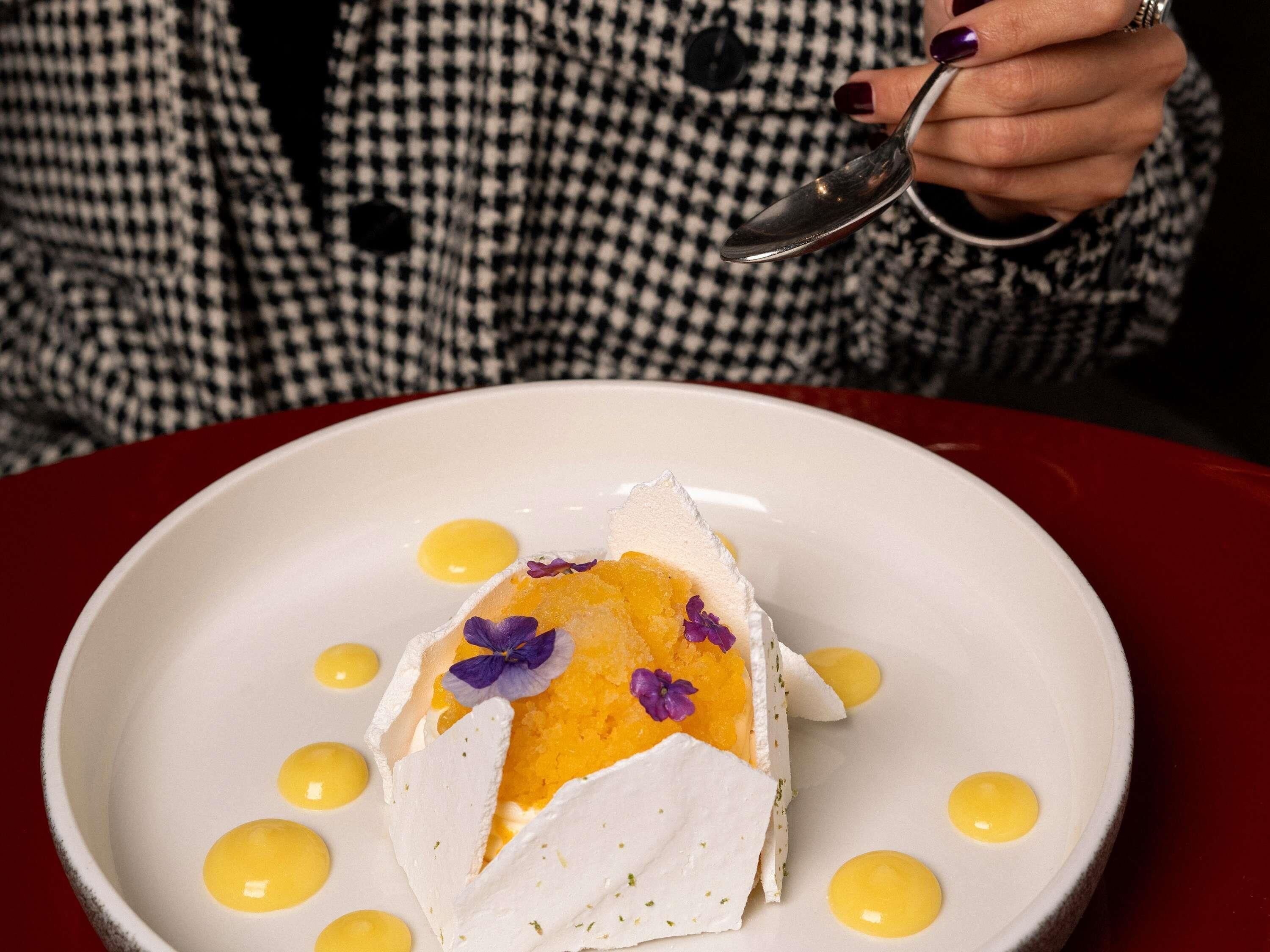 Un plato blanco con un postre, una cuchara y una persona con una camisa de cuadros.