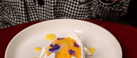 Un plato blanco con un postre, una cuchara y una persona con una camisa de cuadros.