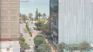 Une rue de la ville bordée d’immeubles imposants, une chaussée réservée aux bus et aux voitures, et une vue sur la mer au loin.