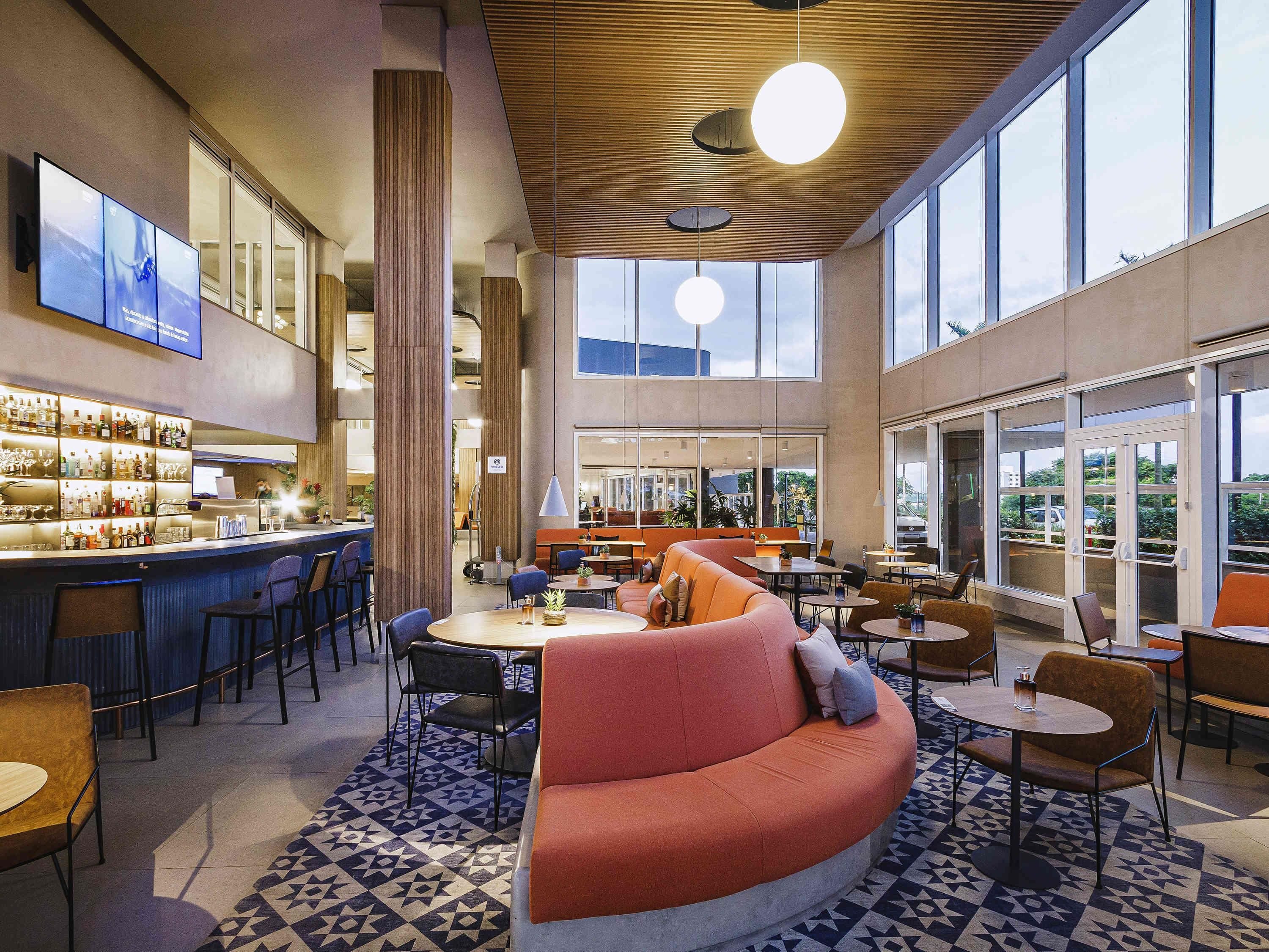 A modern bar area with a counter, seating, and large windows.