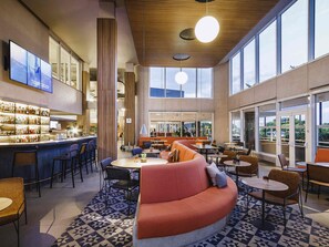 A modern bar area with a counter, seating, and large windows. - Novotel Lencois Paulista (Lencois Paulista)